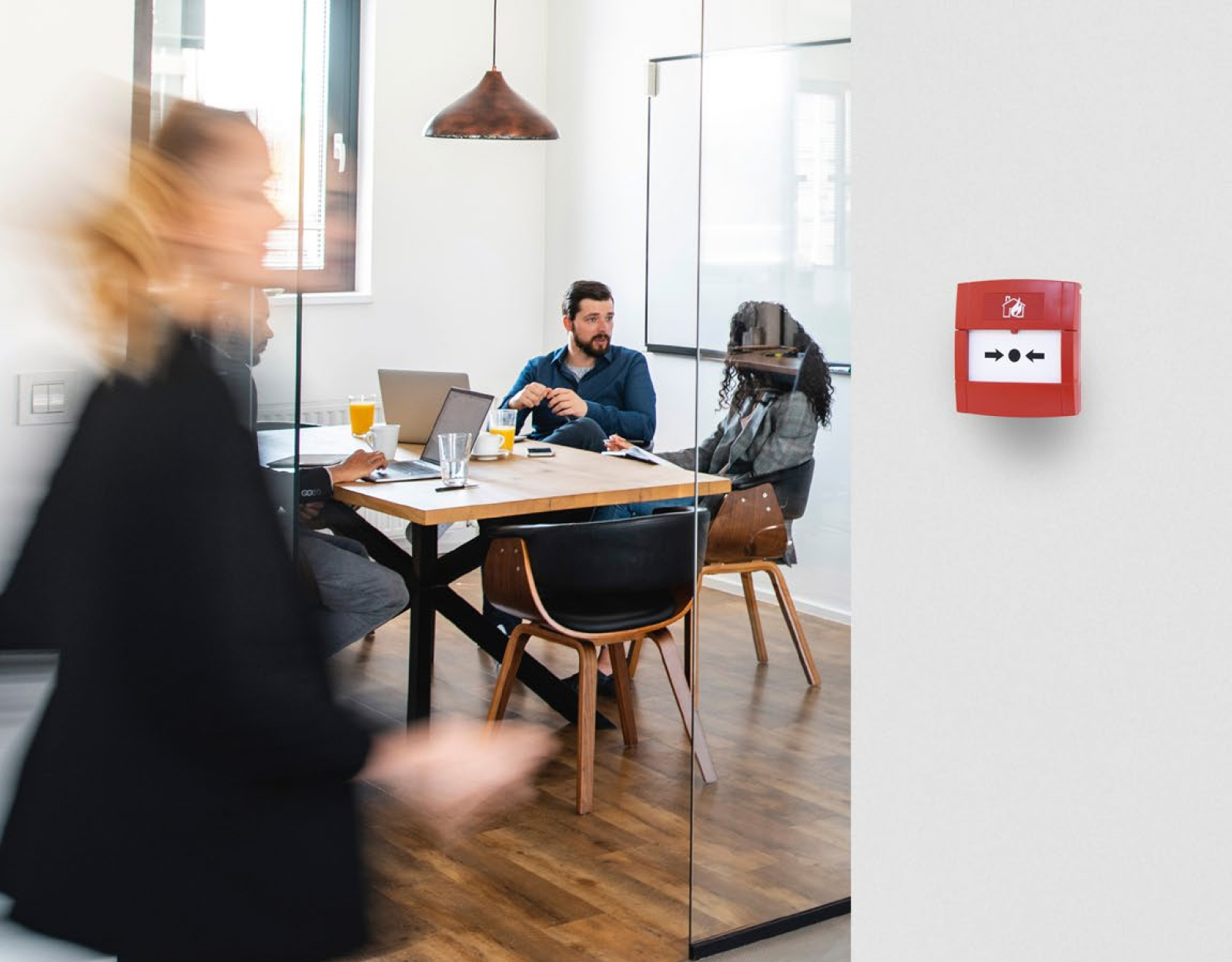 A callpoint unit installed in an office suite, with employees working